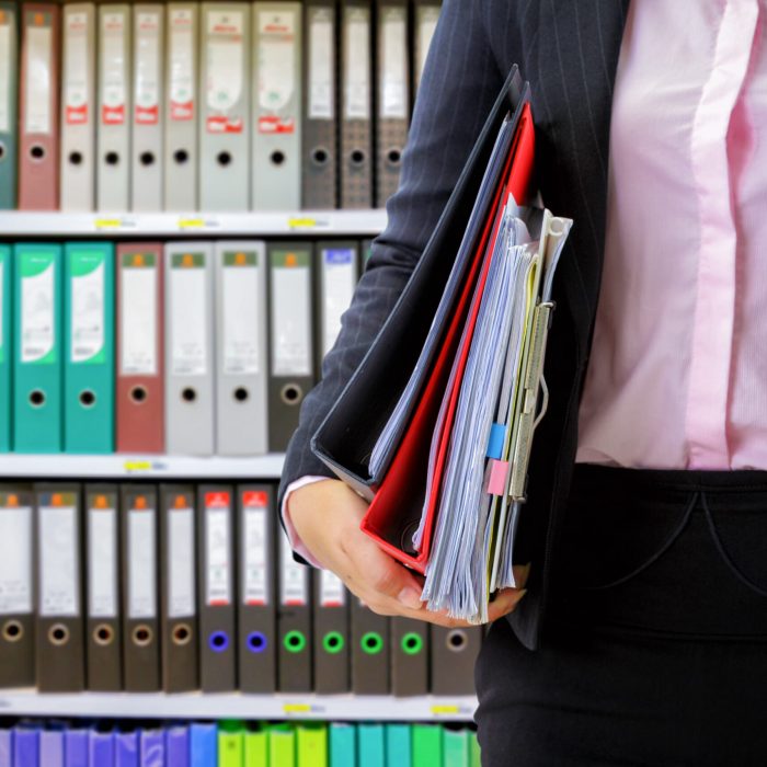 businesswoman holding data files on binder shelves background